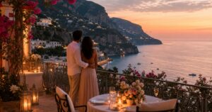 Couple watching sunset from a candlelit coastal hotel terrace above cliffs and sea